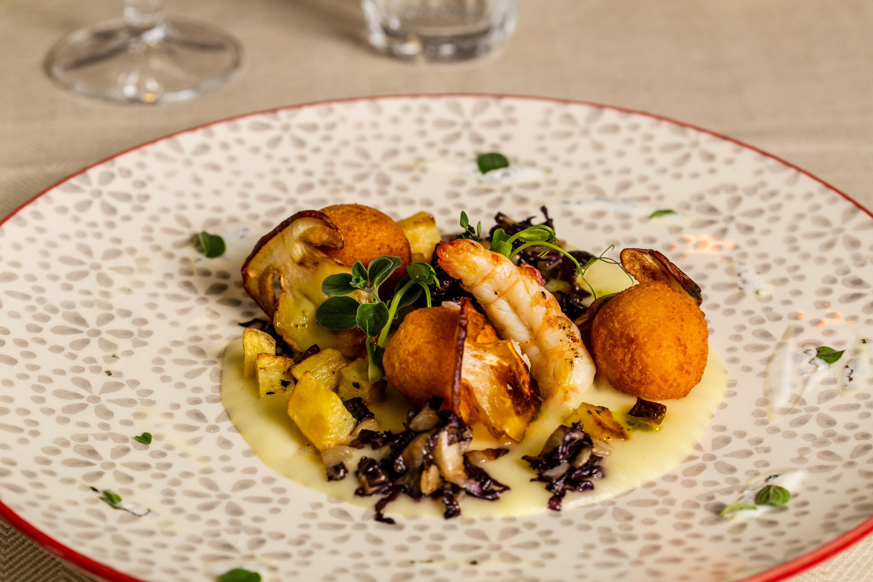 Composta di patate e radicchio, soffritto di porcini ripassati con bon bon di polpo e scampi su crema acida alle erbe