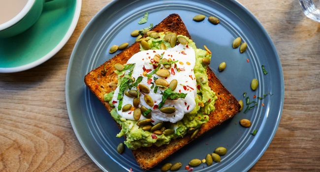 Avocado toast met een gepocheerd ei, pompoenpitten en chili