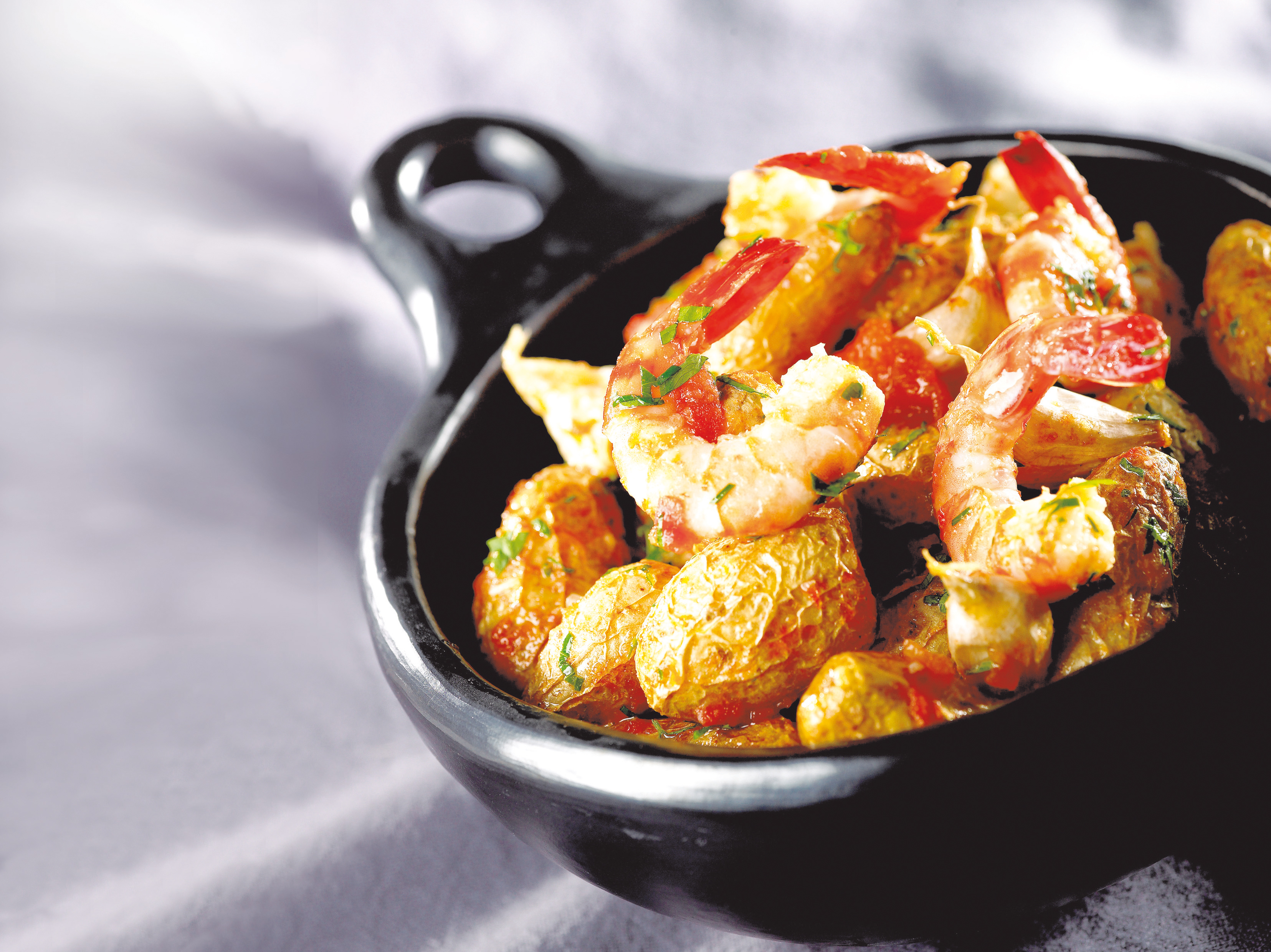 Grenaille-Kartoffeln, ungeschälter Knoblauch, eingelegte Tomaten und Garnelen